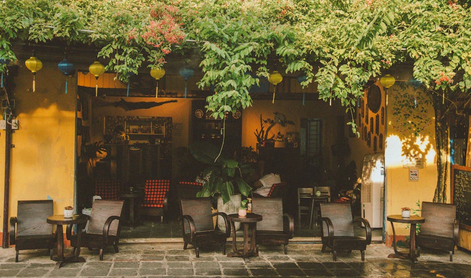 An inviting outdoor café features lush greenery and wooden seating.